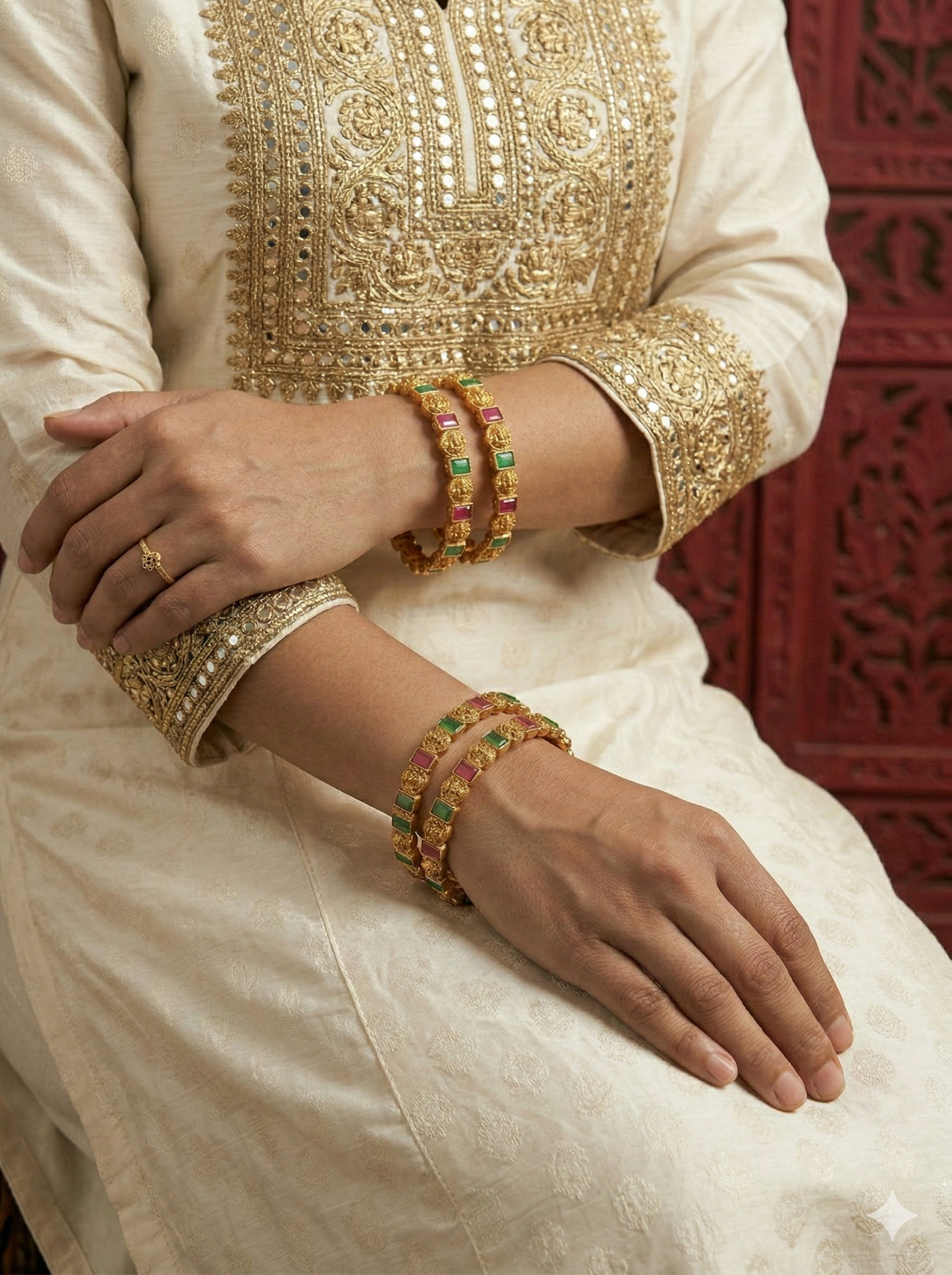 Close-up of a person wearing gold jewelry with a red patterned background