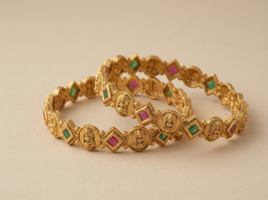 Two gold bracelets with embedded gemstones on a beige background