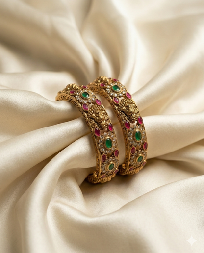Gold bangles with gemstones on a beige fabric background