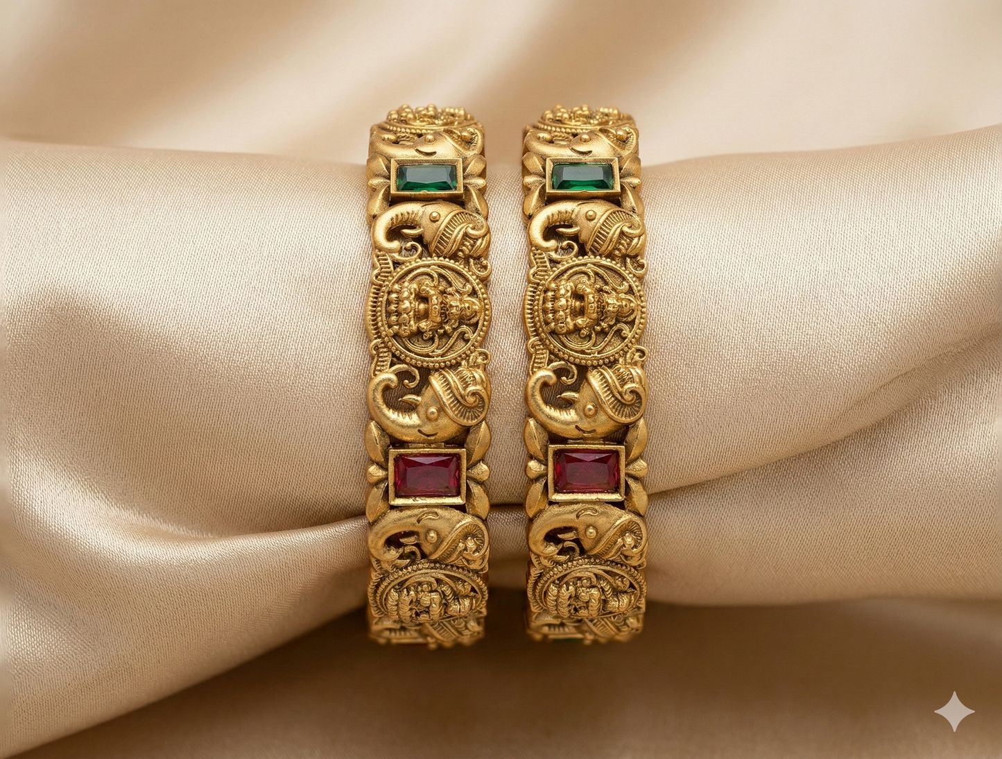 Pair of gold bangles with gemstones on a beige fabric background