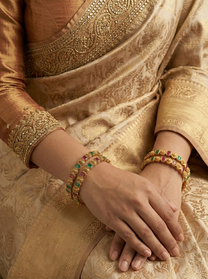 Close-up of a person wearing a gold saree with intricate patterns and jewelry.