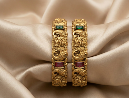 Pair of gold earrings with gemstones on a beige satin background