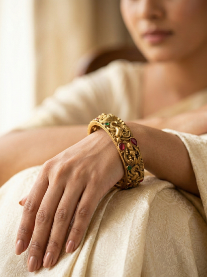 Woman wearing a gold bracelet with gemstones on a neutral background