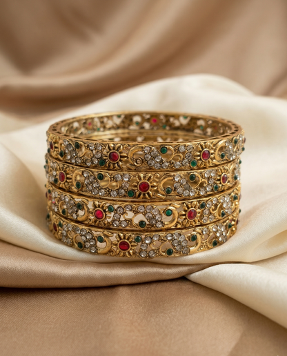 Set of gold bangles with gemstones on a beige fabric background