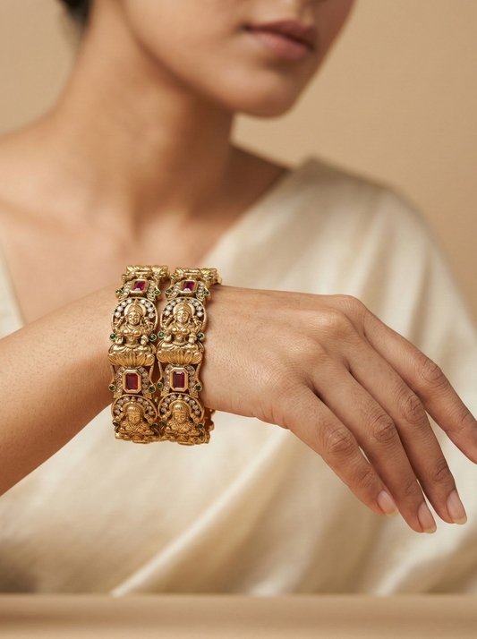 Pair of gold earrings with intricate designs on a beige background