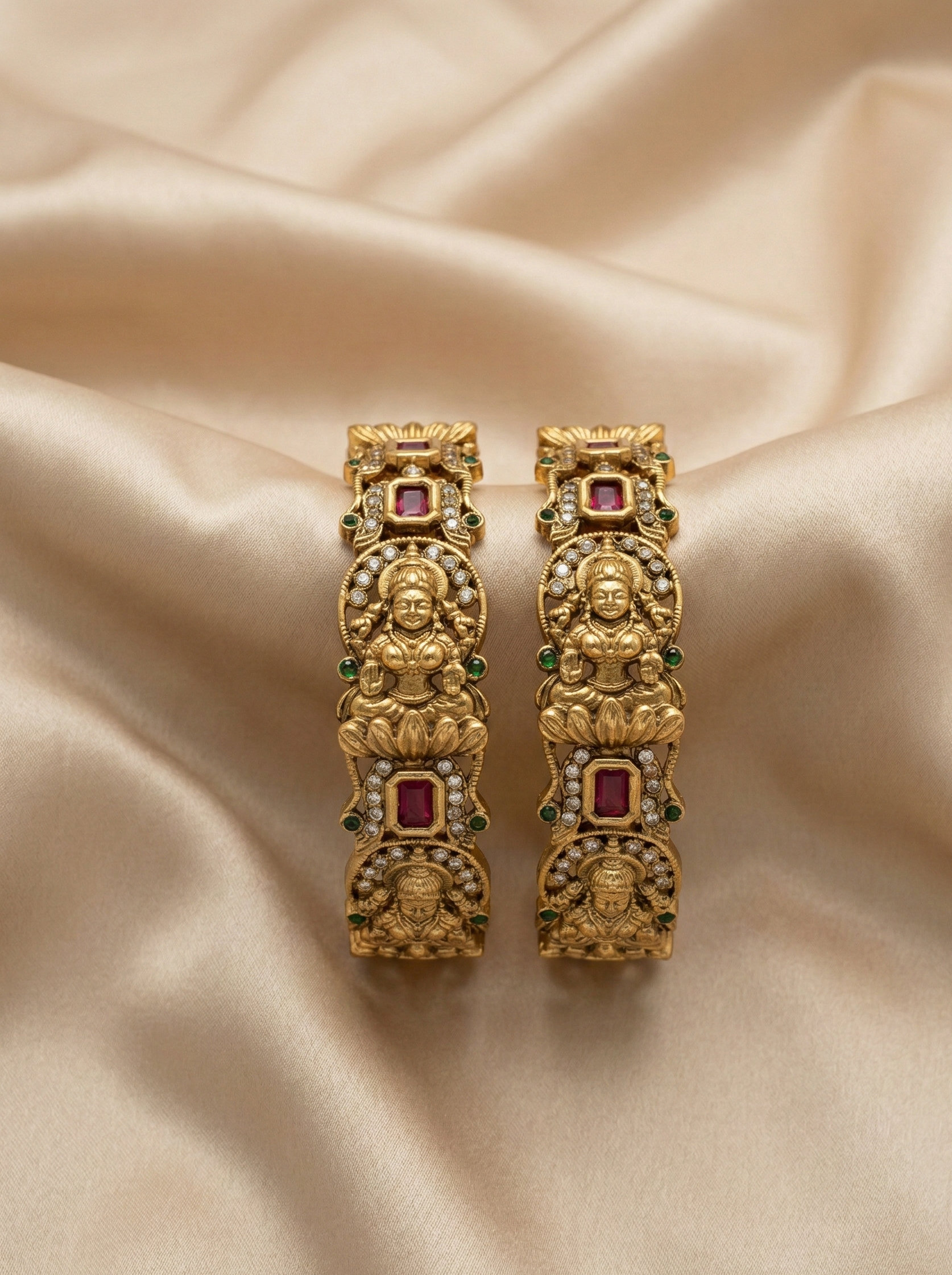 Gold earrings with gemstones on a beige fabric background