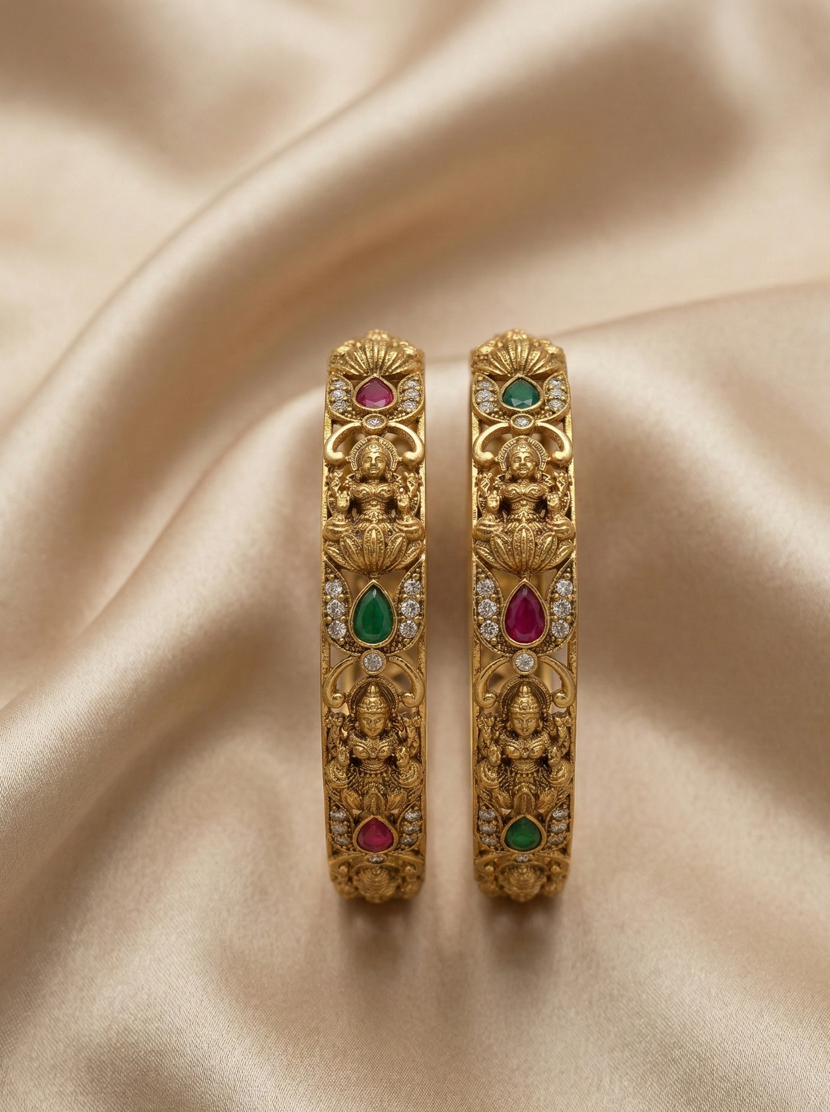 Gold earrings with gemstones on a beige fabric background