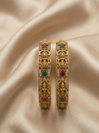 Gold earrings with gemstones on a beige fabric background