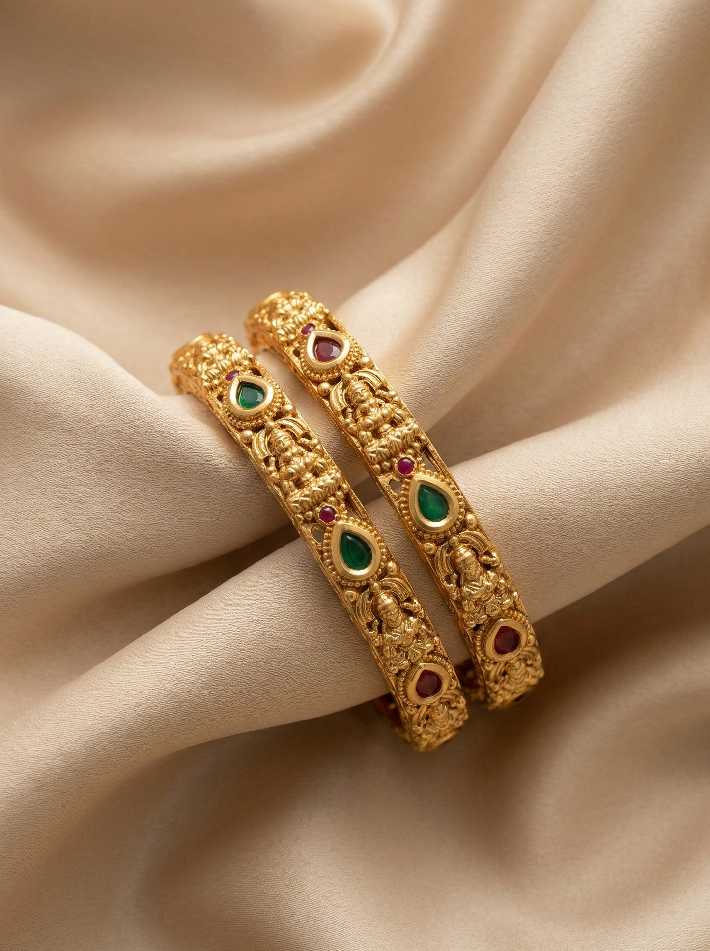 Gold bangles with gemstones on a beige fabric background
