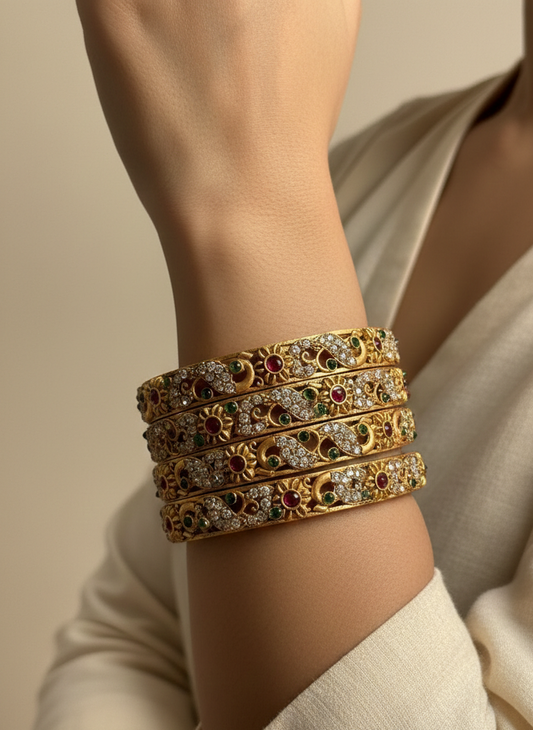Gold bracelet with gemstones on a person's wrist against a neutral background