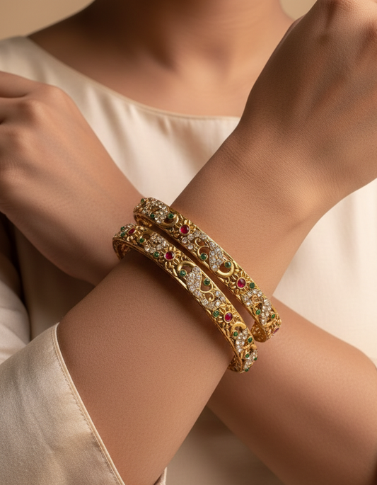 Gold bracelet with gemstones on a person's wrist against a neutral background