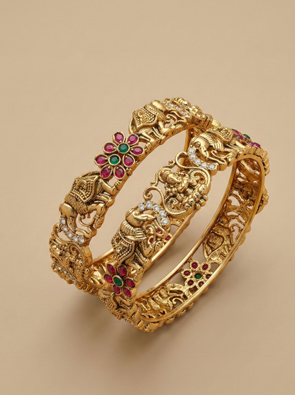 Decorative gold bangles with gemstones on a beige background