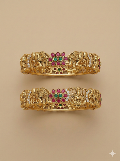 Pair of gold bangles with elephant and deity designs on a beige background