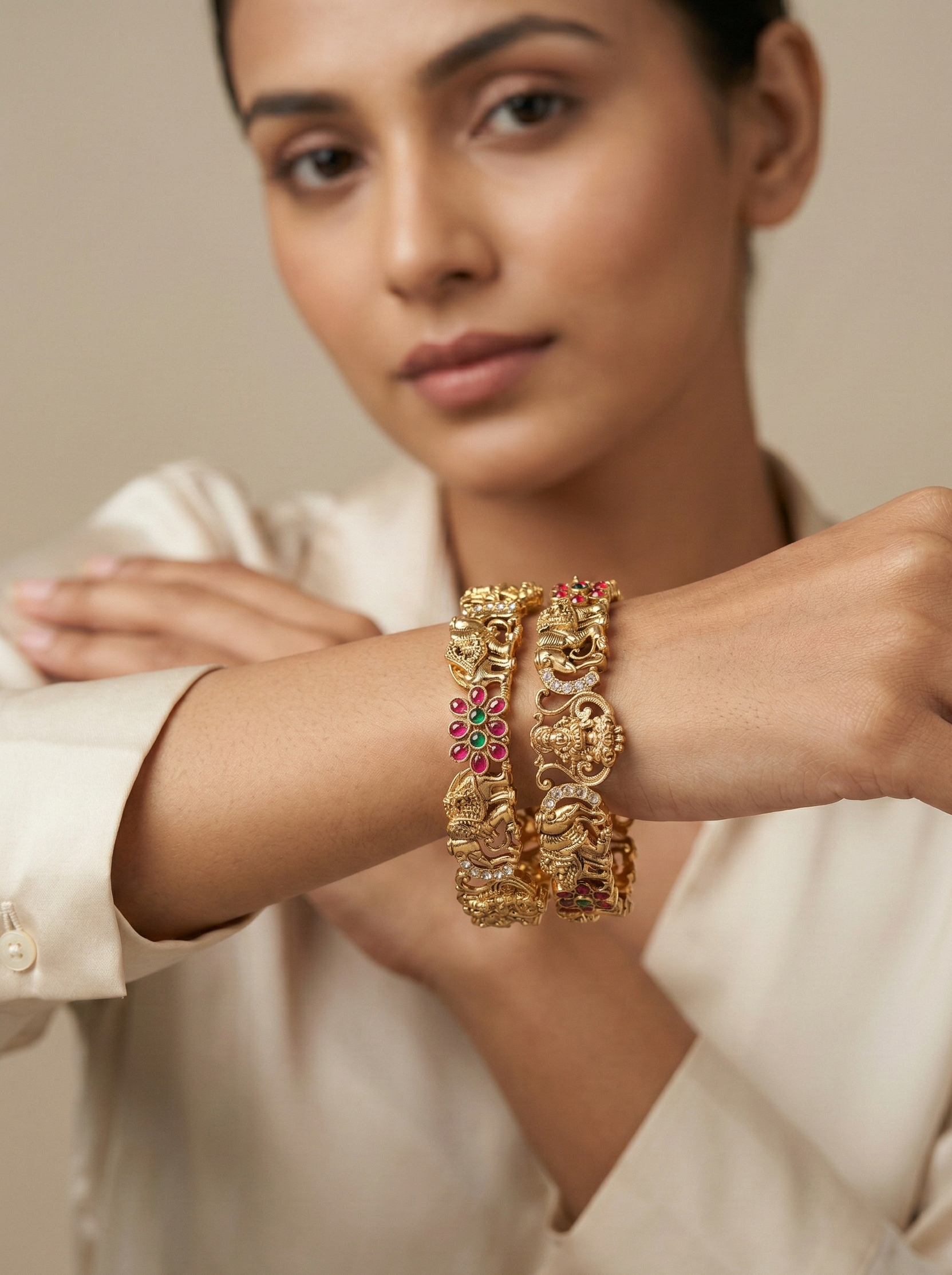 Woman wearing a gold bracelet with red stones on a neutral background