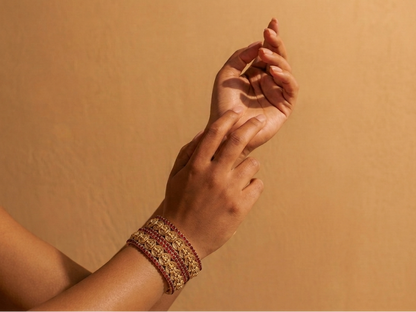 Close-up of a person's hand wearing a bracelet against a beige background
