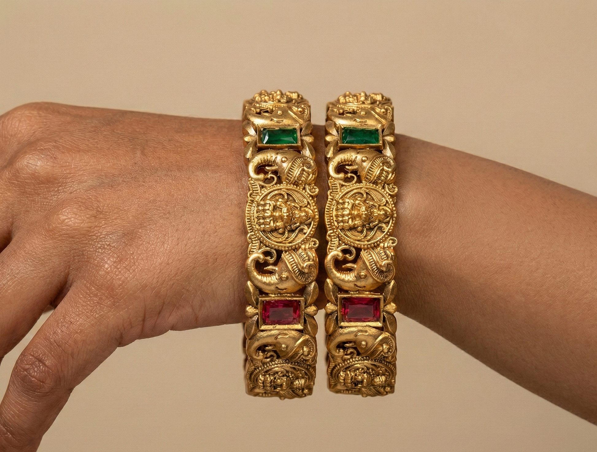 Gold bracelets with gemstones on a beige background