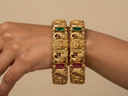 Gold bracelets with gemstones on a beige background