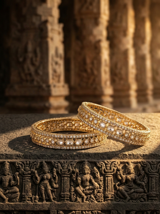 Two gold bangles on a textured surface with architectural background