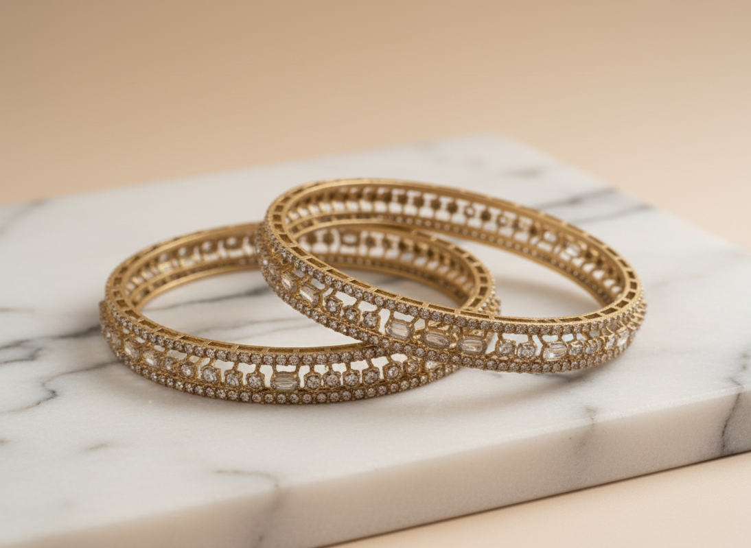 Gold bangles with gemstones on a marble surface
