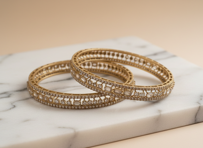 Gold bangles with gemstones on a marble surface